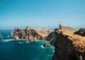 man standing on brown rock formation near blue sea during daytime
