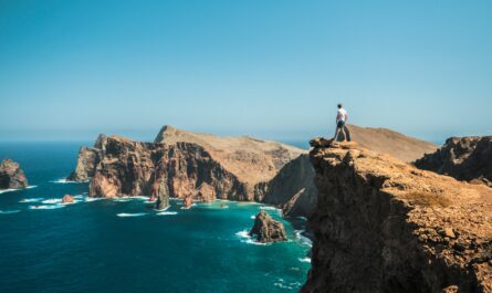 man standing on brown rock formation near blue sea during daytime